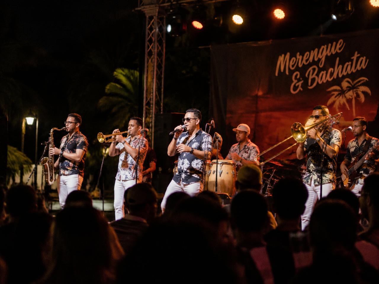 Ten-piece merengue band performing on an outdoor stage at night